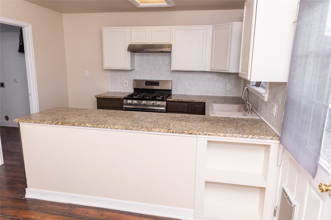 184 Unity Kyle, TX 78640 - Photo 7 of 33 Kitchen with white cabinetry, stainless steel range with gas cooktop, a peninsula, backsplash, and dark wood-style floors