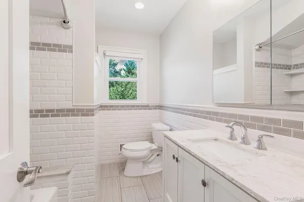 a bathroom with a granite countertop sink a toilet and a mirror