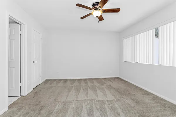 an empty room with windows and fan
