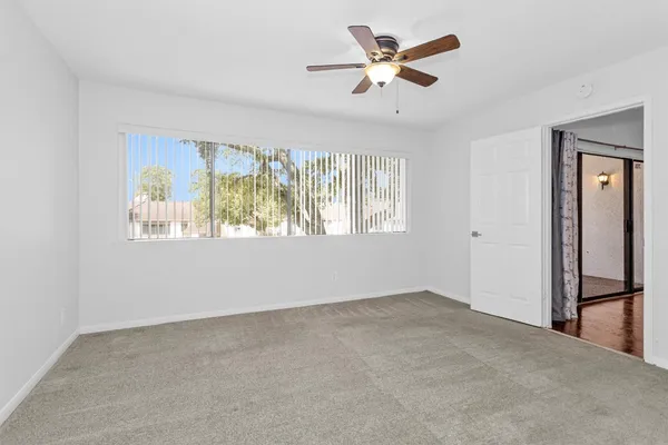 a view of a room with a ceiling fan and carpet