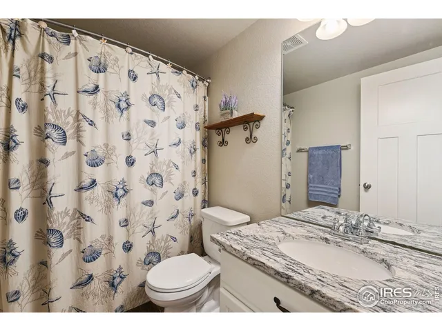 a bathroom with a granite countertop toilet sink and mirror
