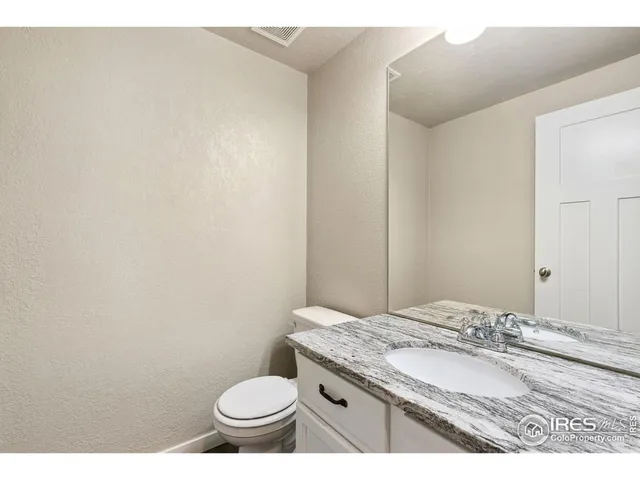 a bathroom with a granite countertop toilet and a sink