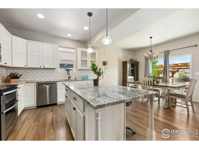 a open kitchen with stainless steel appliances granite countertop a stove refrigerator and white cabinets with wooden floor