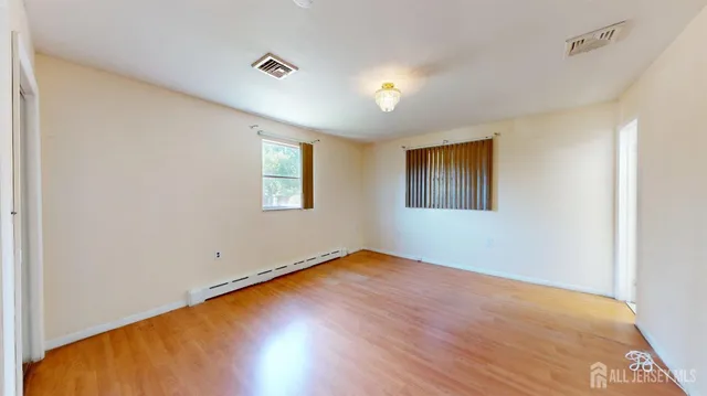 a view of an empty room with wooden floor and a window