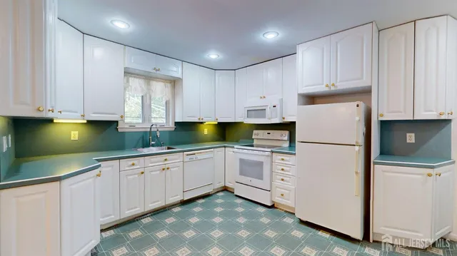a kitchen with white cabinets and white appliances