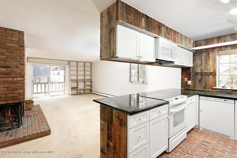 a kitchen that has a sink a stove and white cabinets with wooden floor