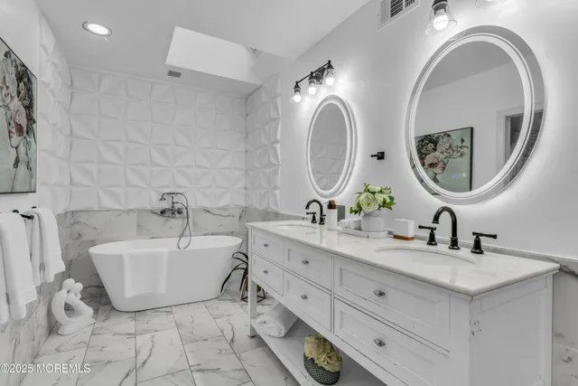 a spacious bathroom with a double vanity sink mirror and bathtub