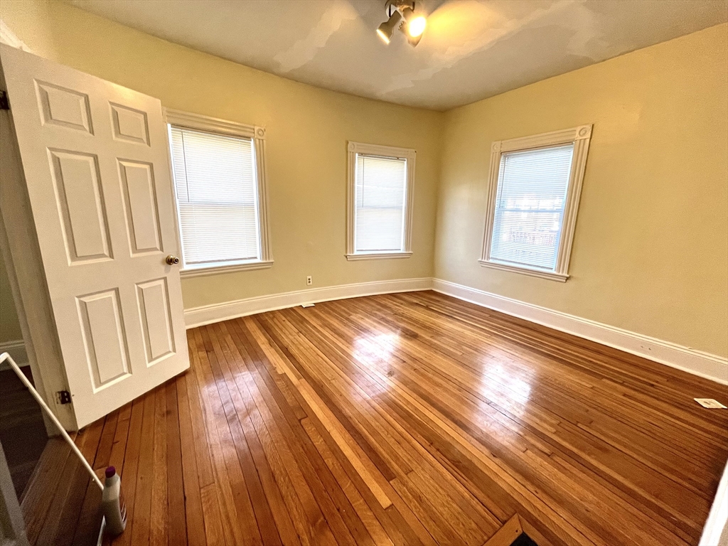 15 Wentworth Street, Unit 1 Boston, MA 02124 - Photo 5 of 14 an empty room with wooden floor and windows