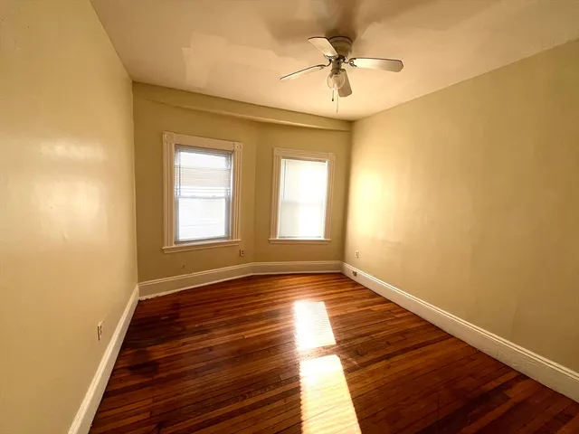 a view of an empty room with window and wooden floor
