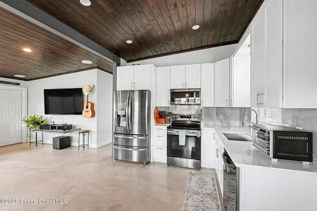 a kitchen with stainless steel appliances a stove a microwave a sink a refrigerator and white cabinets