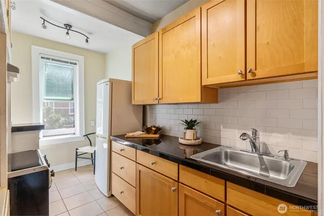 a kitchen with stainless steel appliances granite countertop white cabinets a refrigerator and a sink