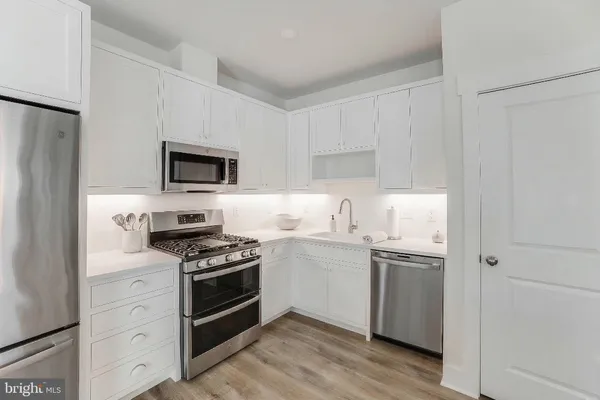 a kitchen with cabinets stainless steel appliances and wooden floor