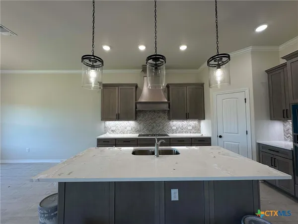 a view of a kitchen with kitchen island a sink stainless steel appliances and a chandelier