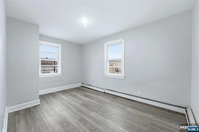 a view of an empty room with wooden floor and closet