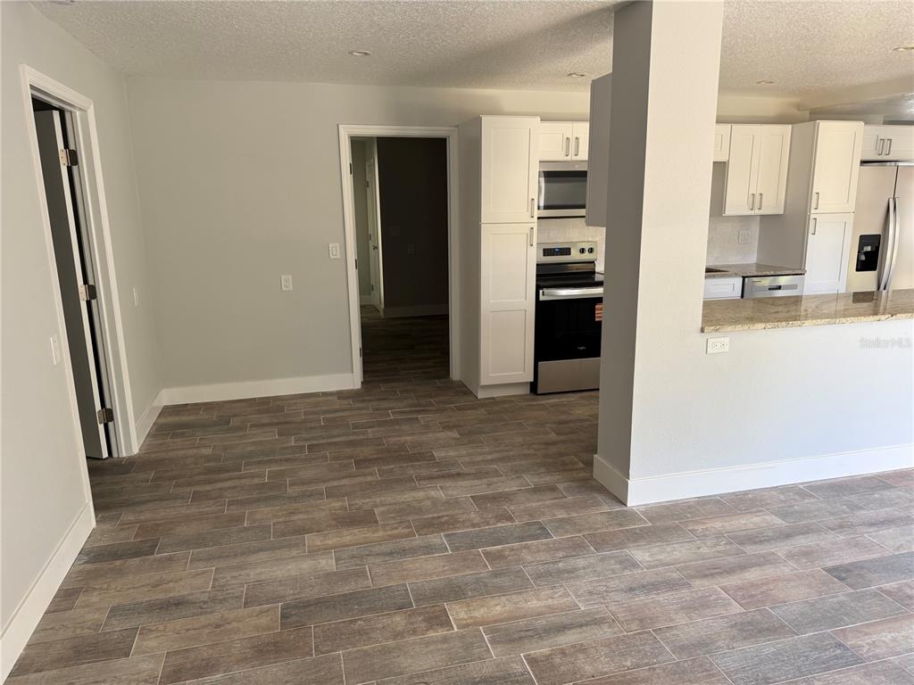 1209 1st Street Indian Rocks Beach, FL 33785 - Photo 4 of 8 an empty room with kitchen view and stainless steel appliances