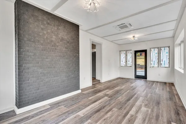 a view of an empty room with window and wooden floor