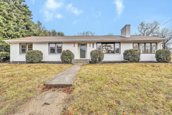 a front view of a house with a yard and potted plants