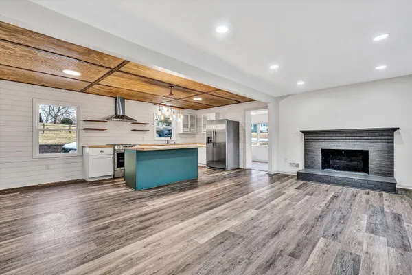 a large kitchen with stainless steel appliances granite countertop a wooden cabinets and a fireplace