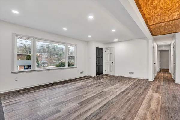 a view of empty room with wooden floor and fan