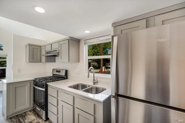 a kitchen with stainless steel appliances a refrigerator a sink a stove and white cabinets