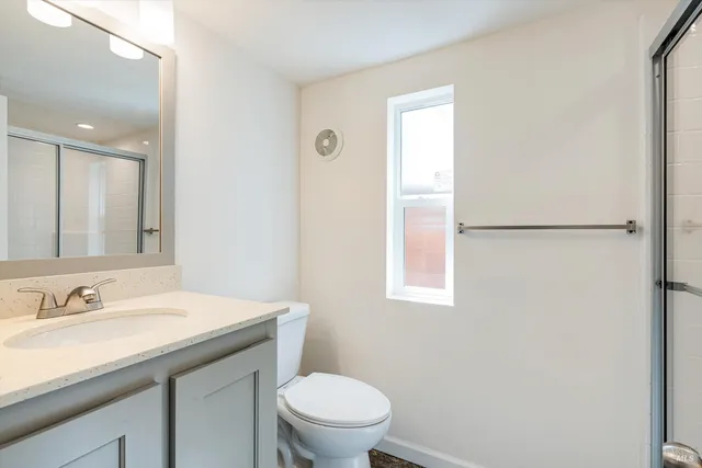 a bathroom with a granite countertop sink toilet and a mirror