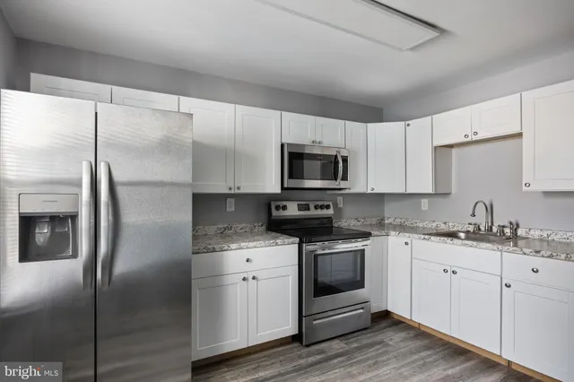 a kitchen with a refrigerator sink and white cabinets