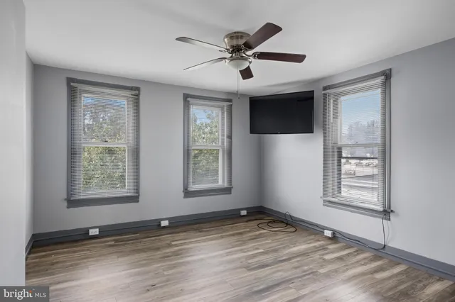 a view of empty room with wooden floor and fan
