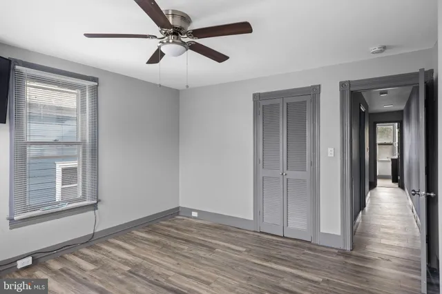 a view of a livingroom with wooden floor a ceiling fan and windows