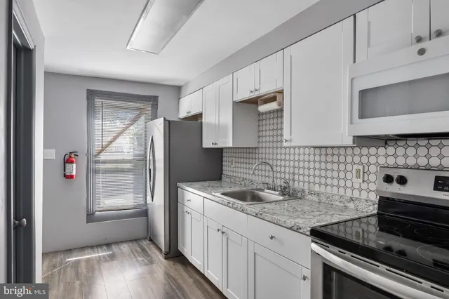 a kitchen with granite countertop a sink stove and refrigerator