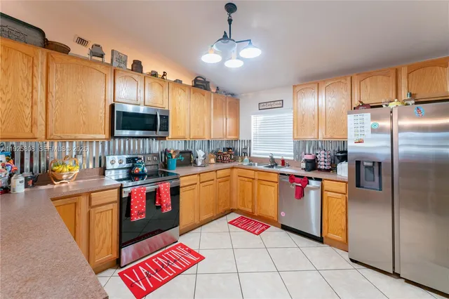 a kitchen with stainless steel appliances granite countertop a refrigerator a stove and a sink with wooden cabinets