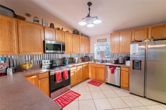 a kitchen with stainless steel appliances granite countertop a sink dishwasher stove and refrigerator with wooden cabinets