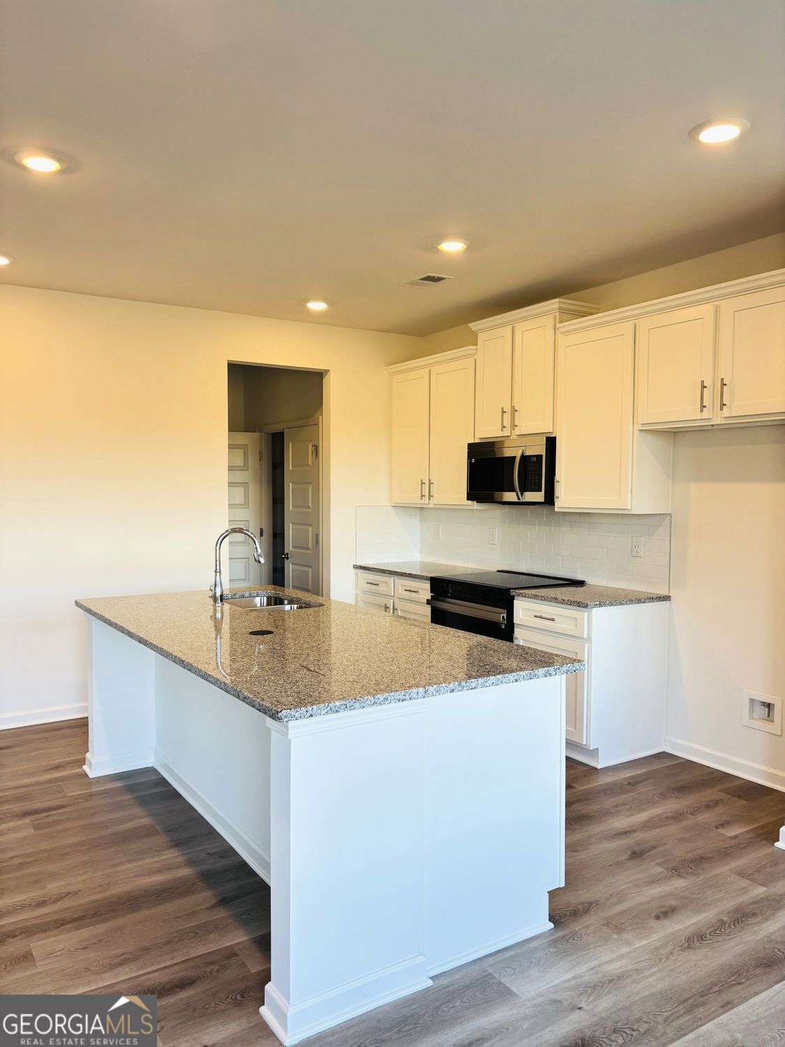 5984 Spring Way Lithonia, GA 30038 - Photo 6 of 17 a kitchen with stainless steel appliances granite countertop a sink a stove a refrigerator a microwave oven with white cabinets and wooden floor