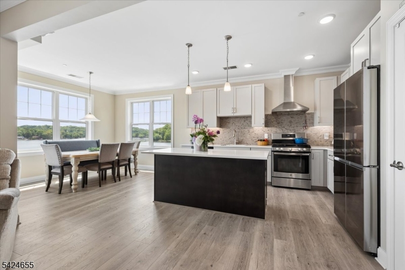401 Mariners Pointe Hopatcong, NJ 07843 - Photo 12 of 42 a kitchen with stainless steel appliances granite countertop a refrigerator a stove top oven a sink dishwasher a dining table and chairs with wooden floor