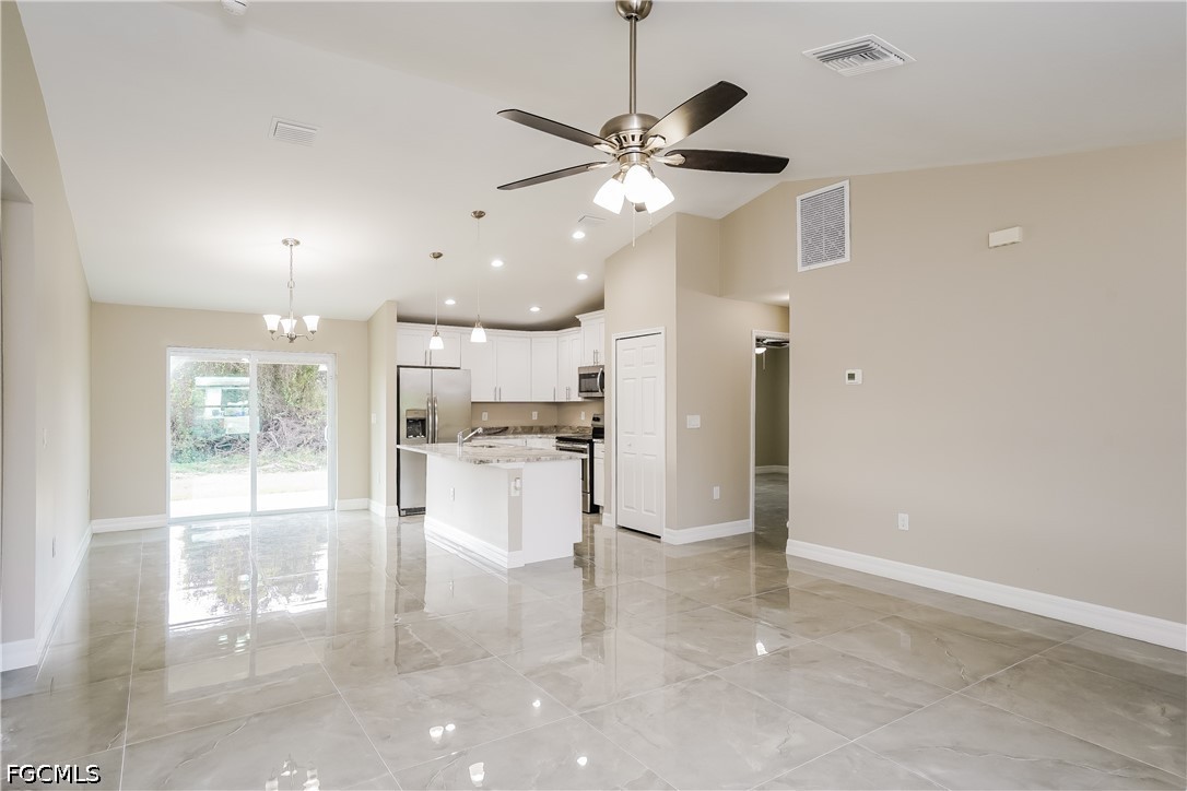 3707 10th Street Southwest Lehigh Acres, FL 33976 - Photo 7 of 15 a view of a kitchen with kitchen island a counter top space appliances and a ceiling fan