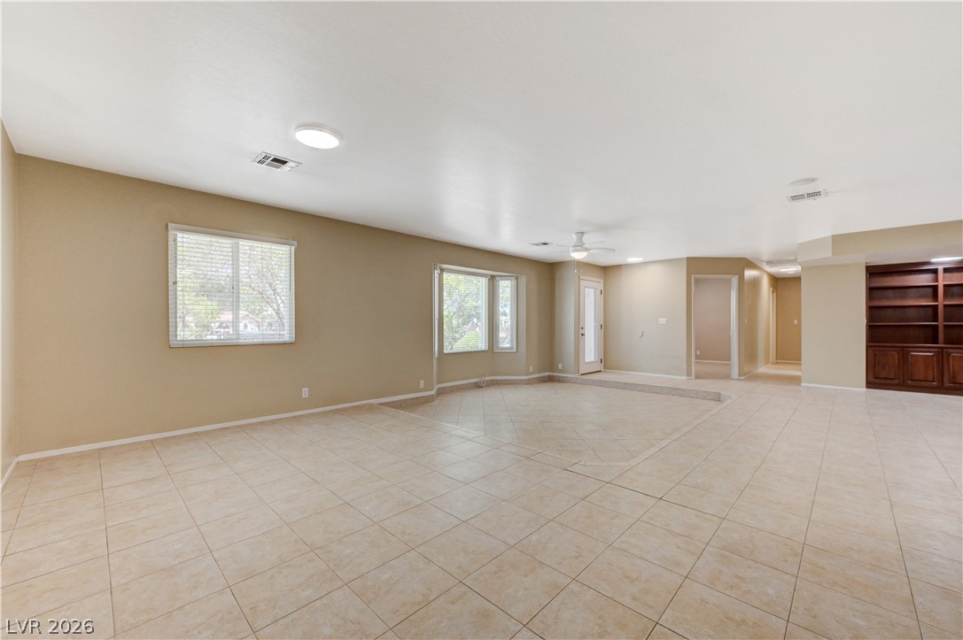 7631 Bermuda Road Las Vegas, NV 89123 - Photo 14 of 64 A spacious living area featuring tiled floors, multiple windows, and a built-in wooden bookcase.