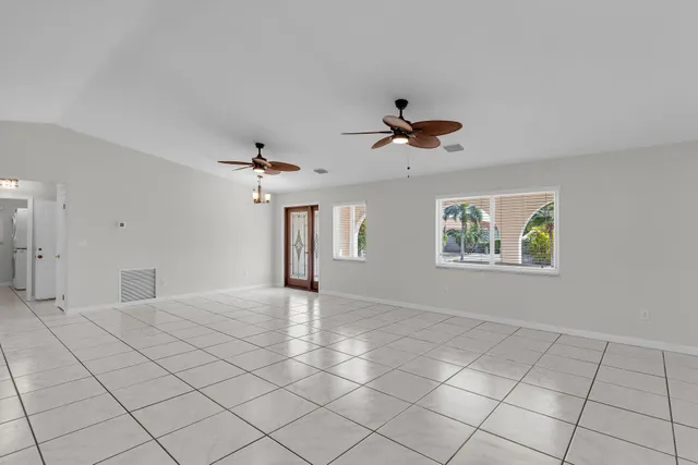 an empty room with windows and ceiling fan