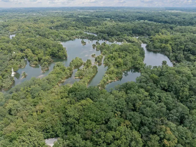 an aerial view of a houses with a yard and lake