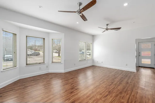 a view of an empty room with wooden floor and a window
