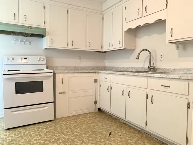 a kitchen with granite countertop white cabinets and white appliances