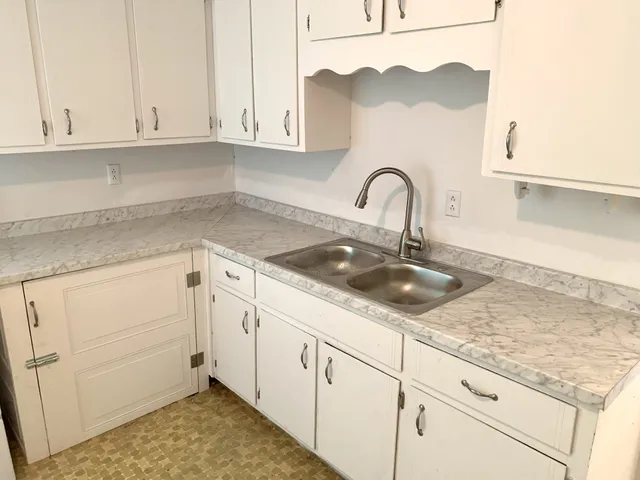 a kitchen with granite countertop white cabinets and a sink