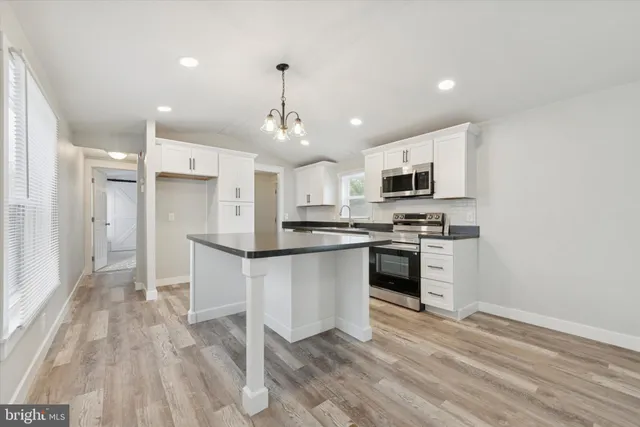 a kitchen with stainless steel appliances kitchen island granite countertop a stove and a refrigerator