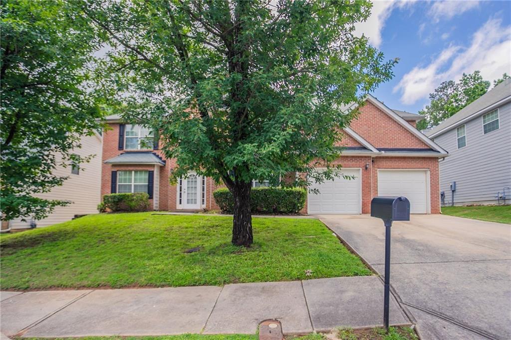 a front view of a house with garden and trees