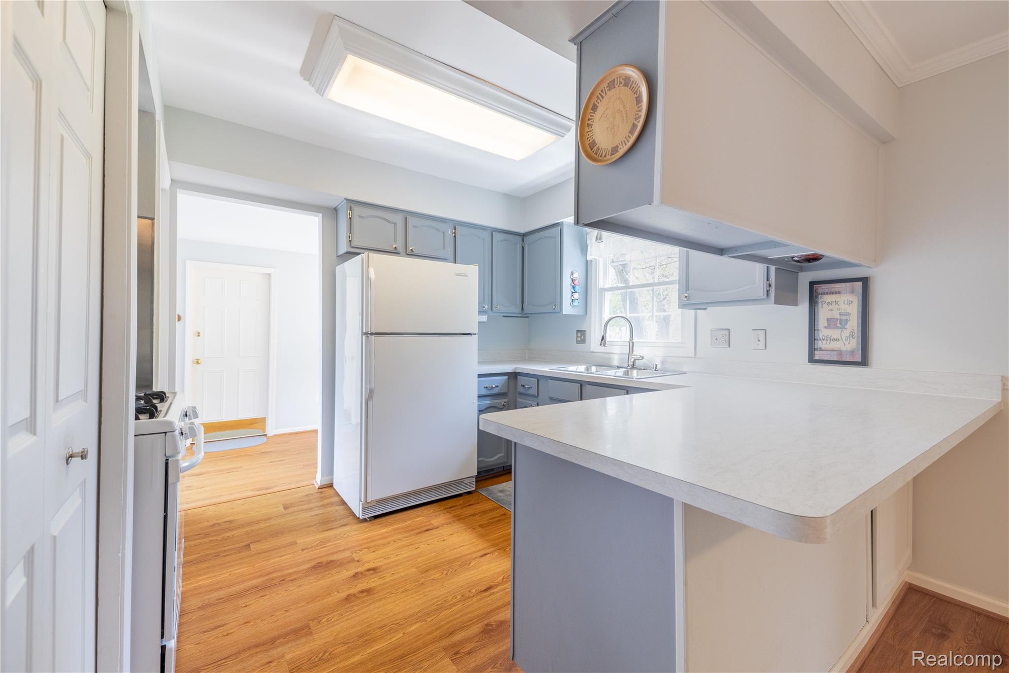 27758 Johnson Road Grosse Ile, MI 48138 - Photo 19 of 49 Kitchen featuring light countertops, a peninsula, white appliances, light wood-style floors, and a breakfast bar