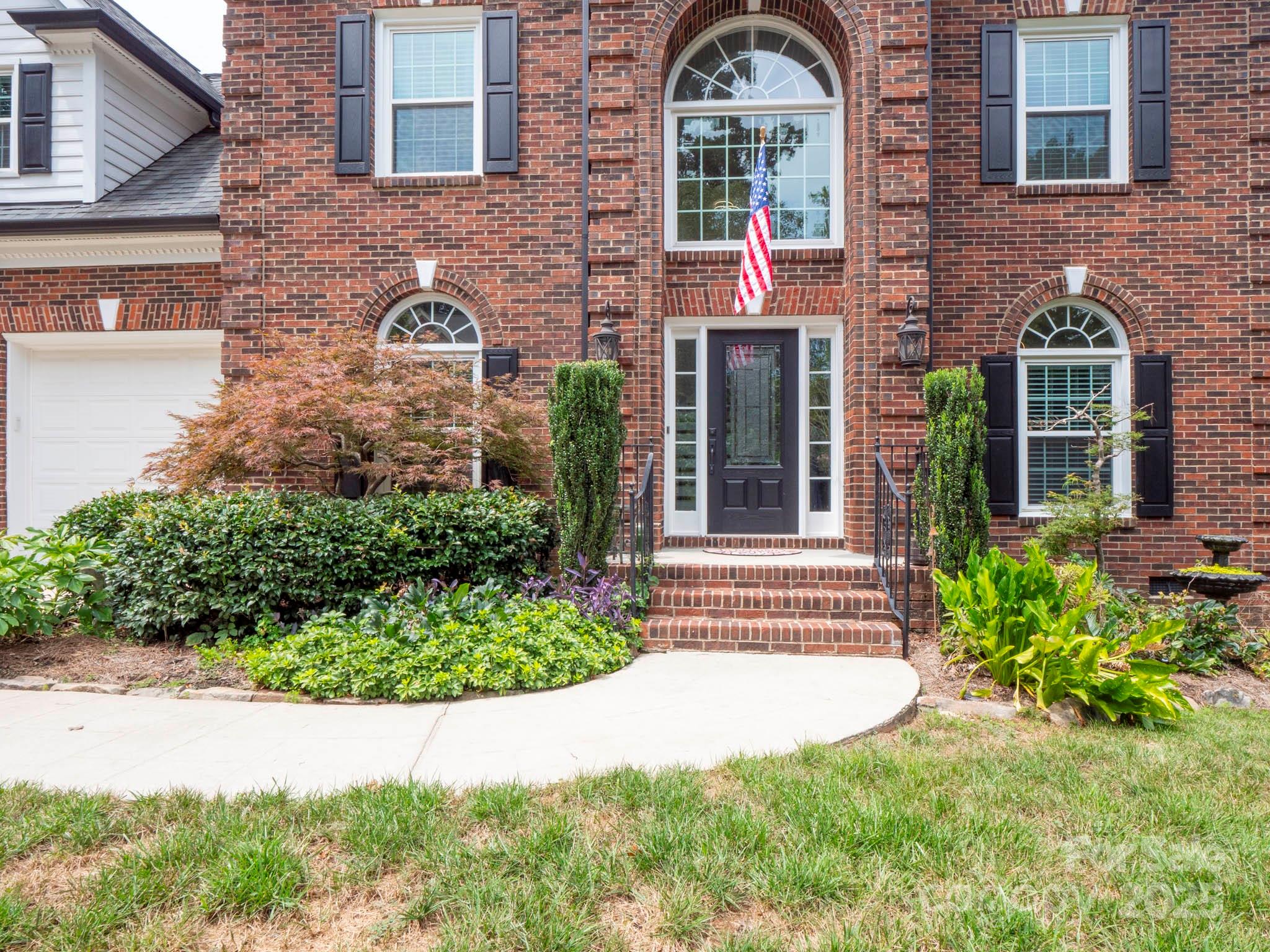 9014 Cardinal Ridge Court Charlotte, NC 28270 - Photo 4 of 45 a view of a brick house with plants and large tree
