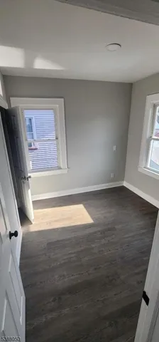 a view of empty room with window and wooden floor