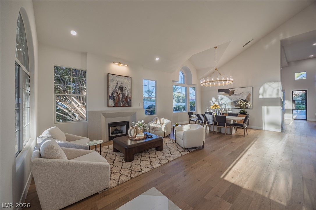 8800 Lusso Las Vegas, NV 89134 - Photo 17 of 85 Living room featuring hardwood / wood-style flooring, a fireplace, lofted ceiling, and a chandelier