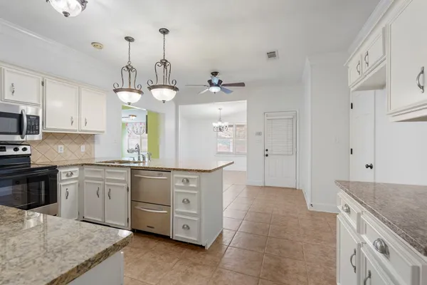 a large kitchen with granite countertop a stove a sink dishwasher and a refrigerator