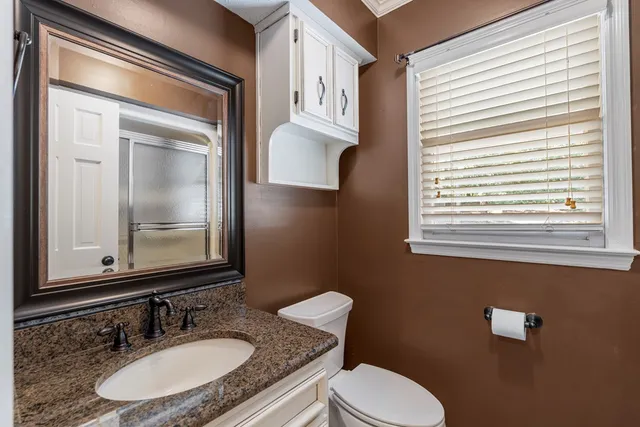 a bathroom with a granite countertop toilet sink and mirror