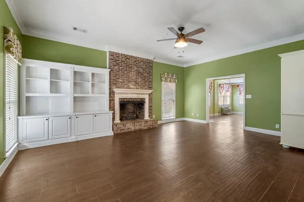 an empty room with wooden floor fireplace and windows