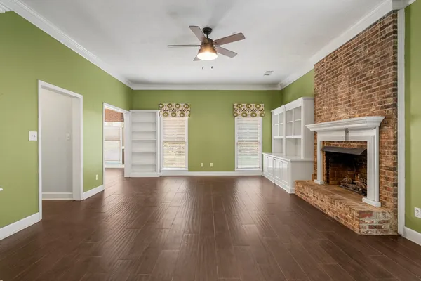 a view of empty room with fireplace and wooden floor